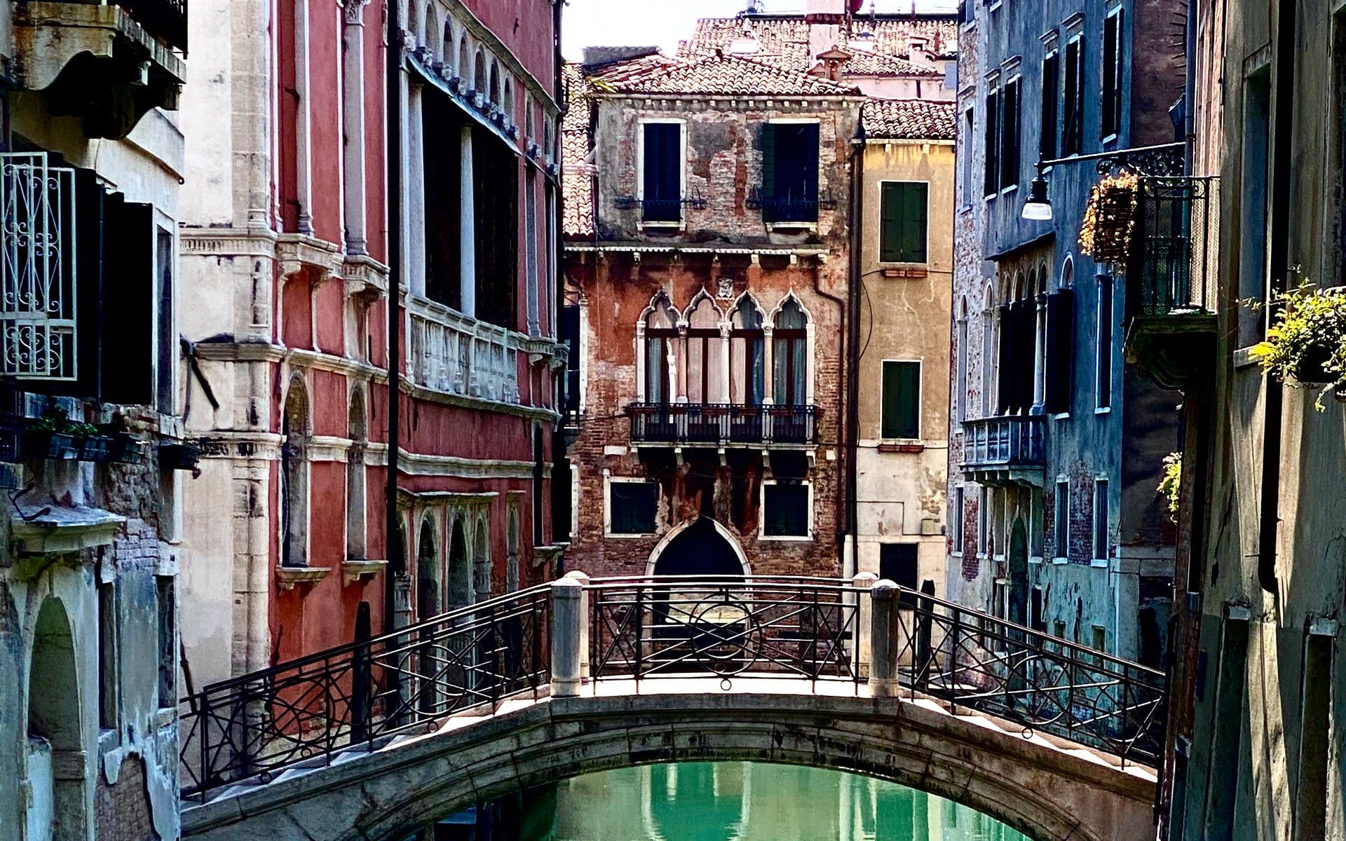 Scenic view of a Venetian canal with a stone bridge and colorful historic buildings in Venice, Italy.