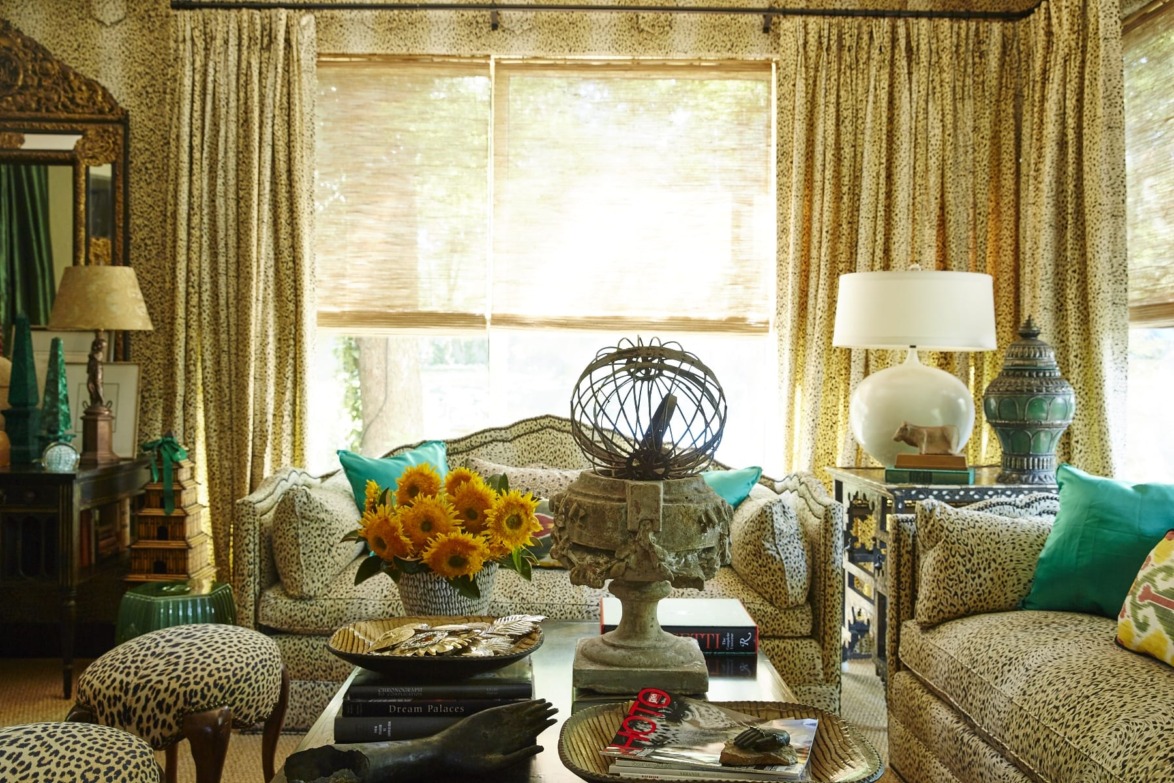 Living room with animal print decor, sunflower bouquet on coffee table, and earth-toned curtains with sunlight streaming through.