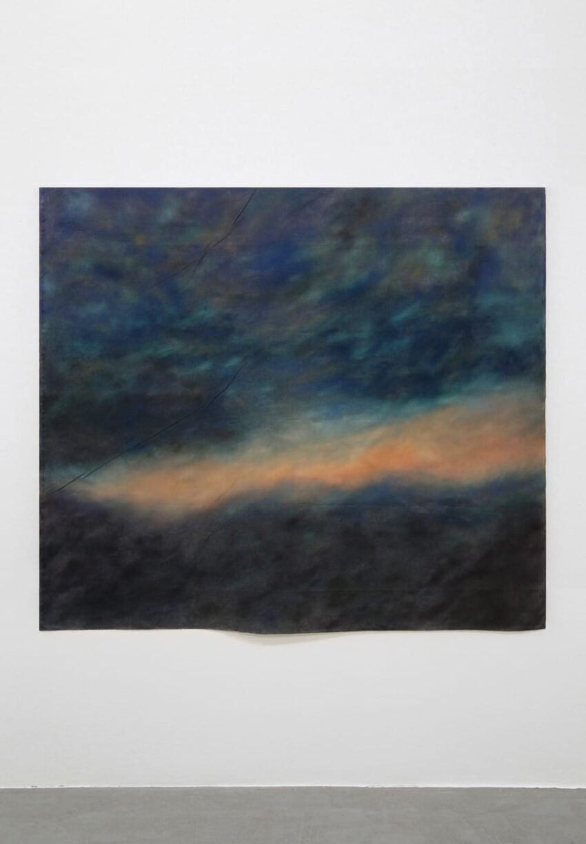 Abstract painting with dark blue, green, and orange hues, resembling a moody sky on a canvas displayed on a white wall.