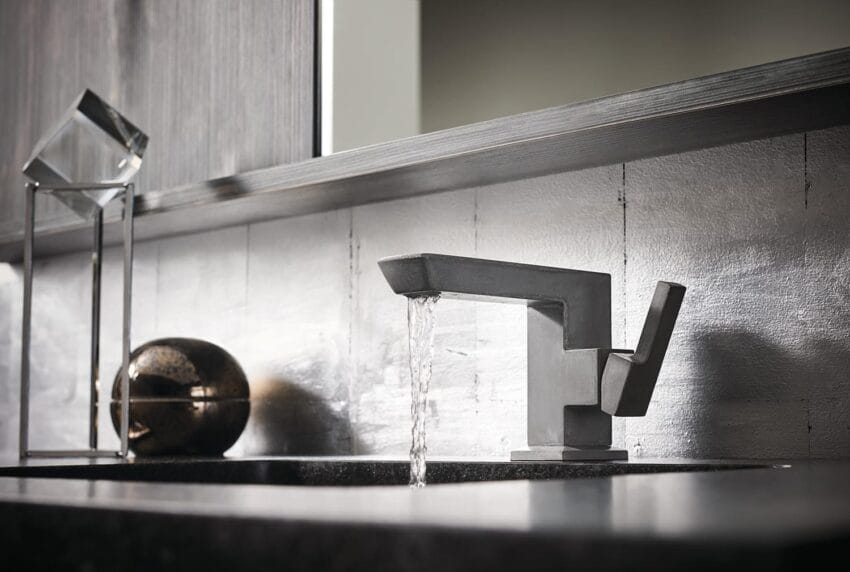 Modern bathroom faucet with running water on a sleek granite countertop, accompanied by decorative elements in a stylish setting.