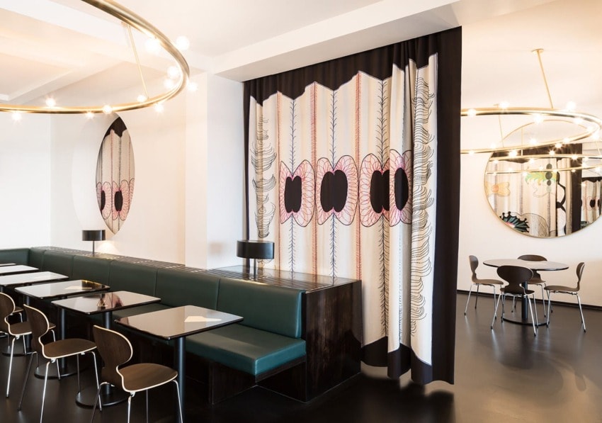 Modern cafe interior with unique patterned curtains, sleek furniture, and decorative mirrors creating a stylish ambiance.