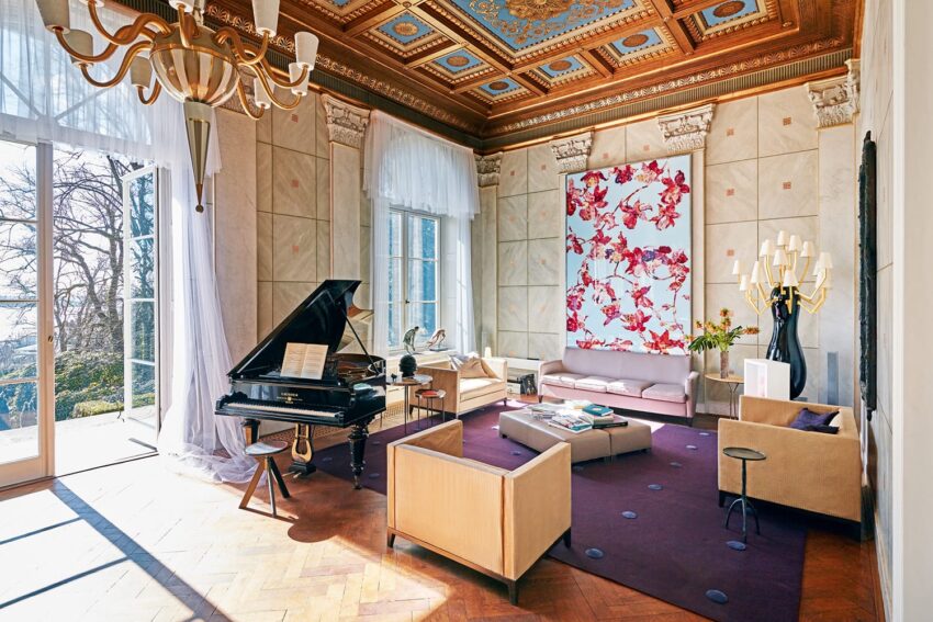 Elegant living room with grand piano, modern furniture, large floral artwork, and ornate ceiling design.