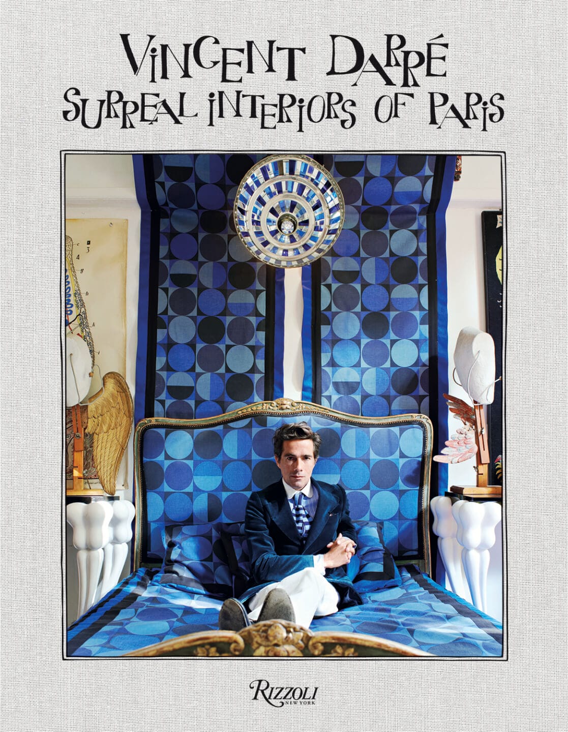 Book cover of "Vincent Darré: Surreal Interiors of Paris" featuring a man seated on a patterned bed.