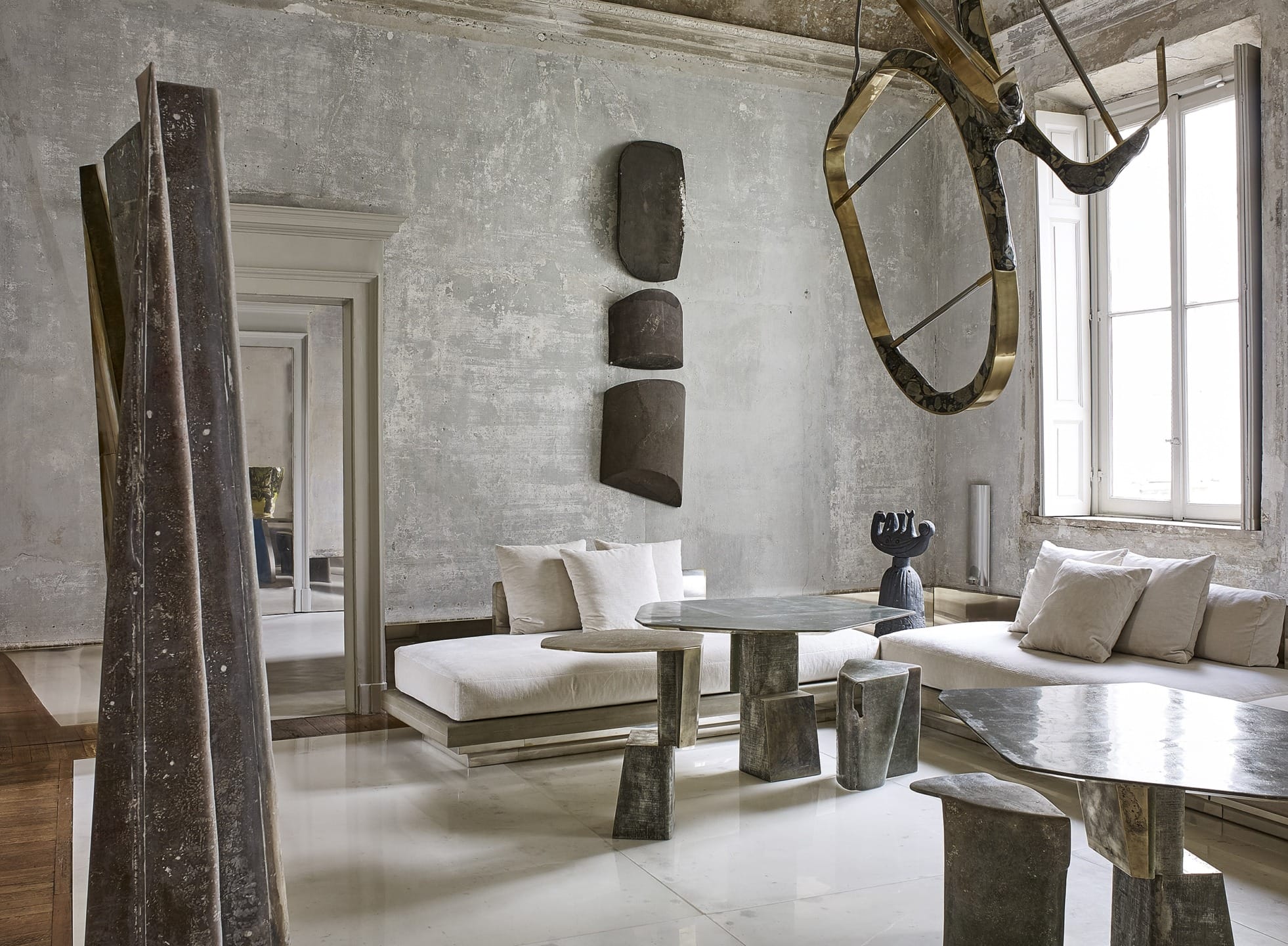 Modern living room with abstract sculptures, minimalist furniture, and large window bringing in natural light.