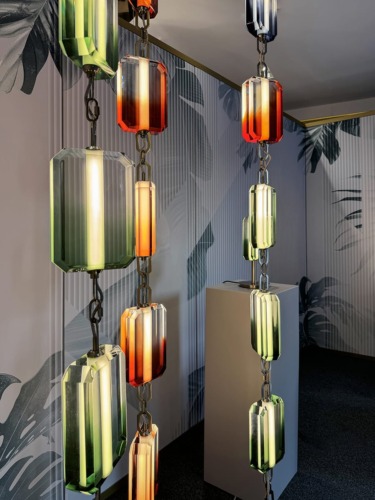 Colorful geometric pendant lights hanging in a modern room with patterned walls.