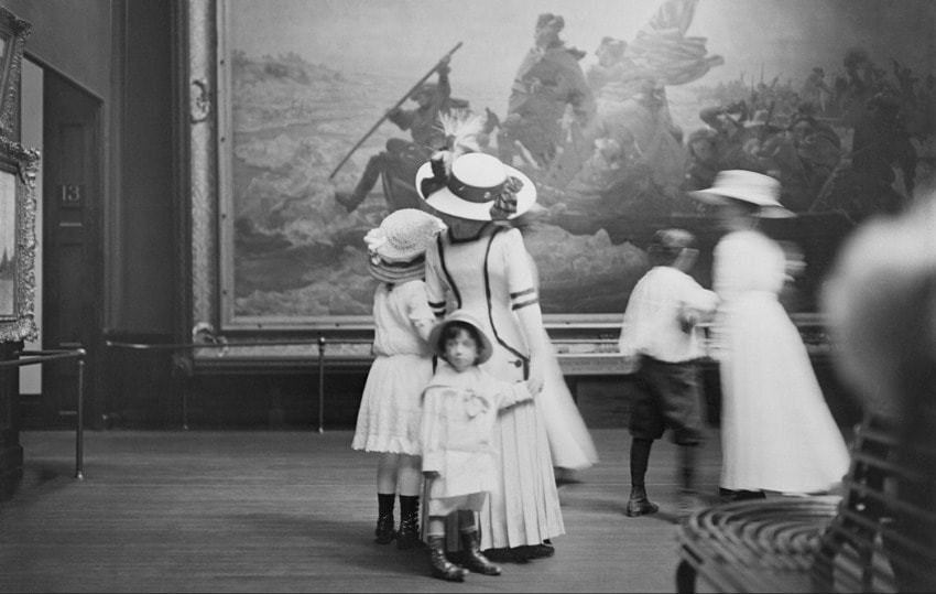 People in vintage clothing admire large painting in art gallery, 1910s style outfits, historical artwork setting.