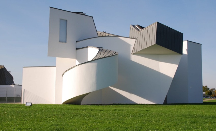 Modern art museum with white geometric architecture and spiral ramp under a clear blue sky.
