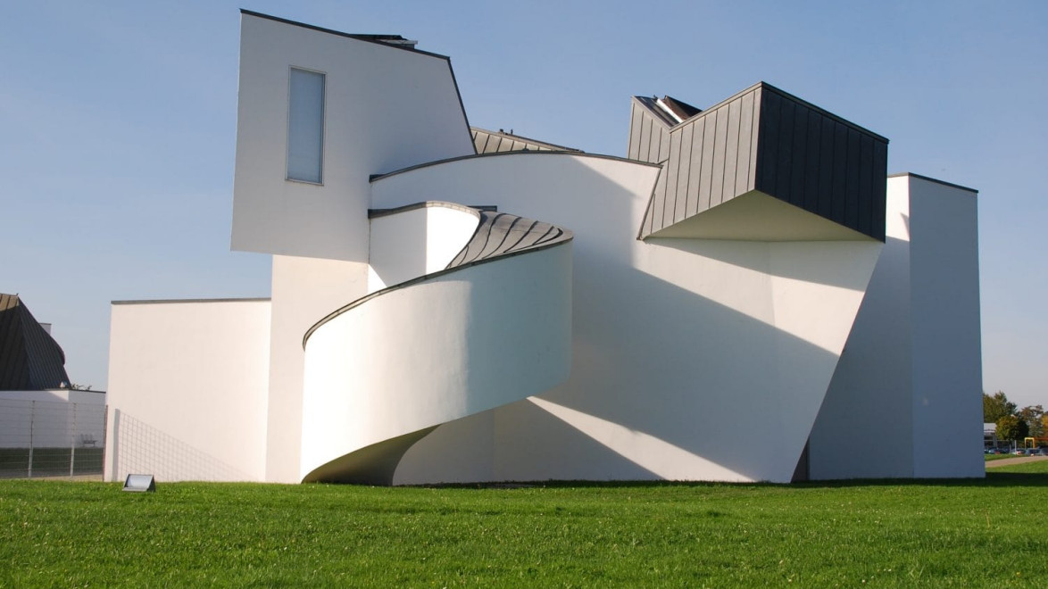 Modern art museum with white geometric architecture and spiral ramp under a clear blue sky.