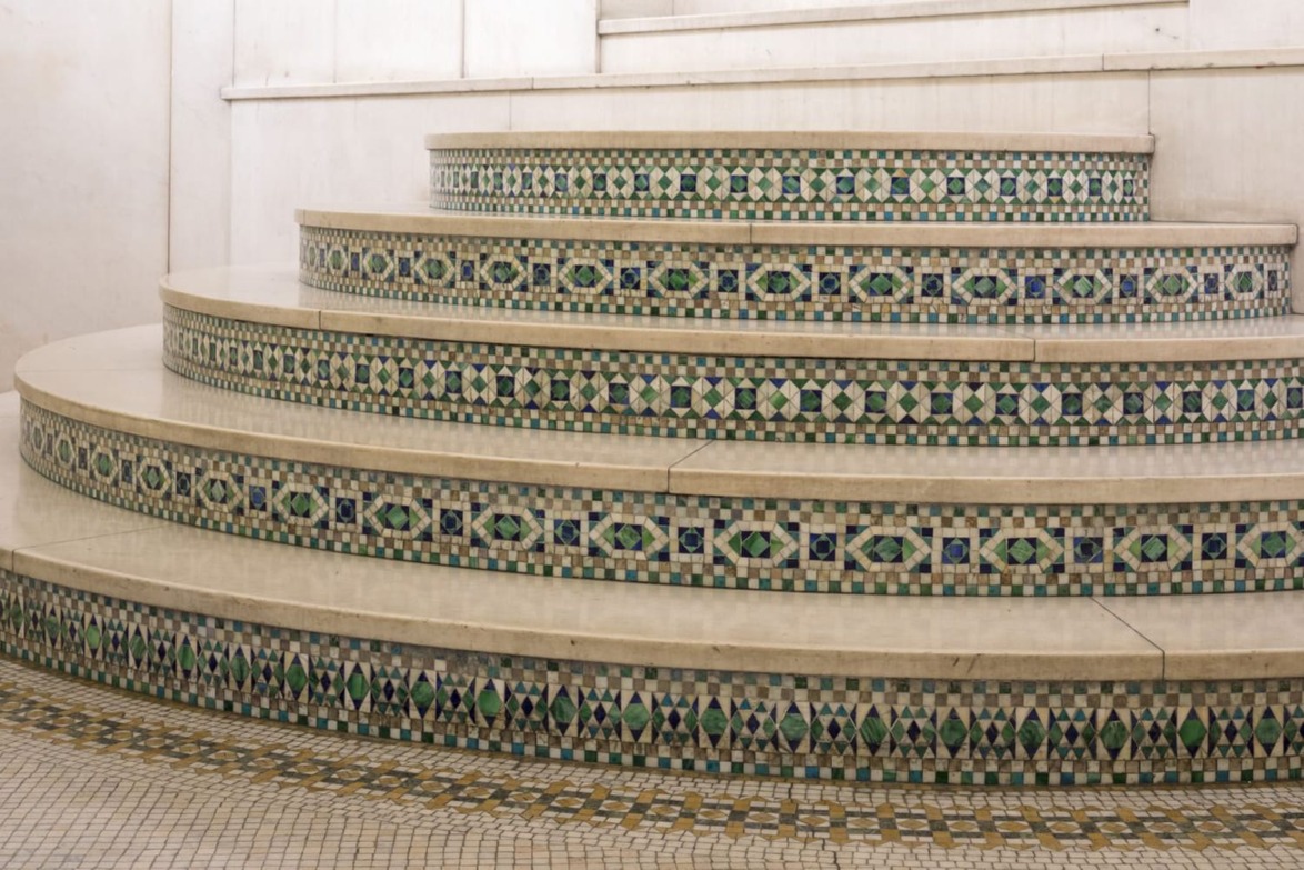 Round stairs with intricate green and blue mosaic patterns and white steps in a geometric design.