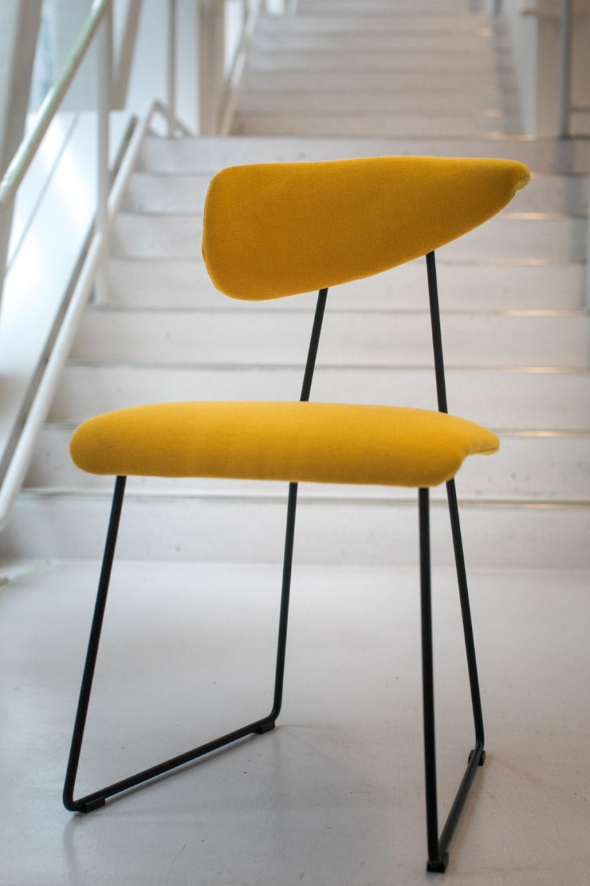 Yellow modern chair with black metal frame on a staircase background.