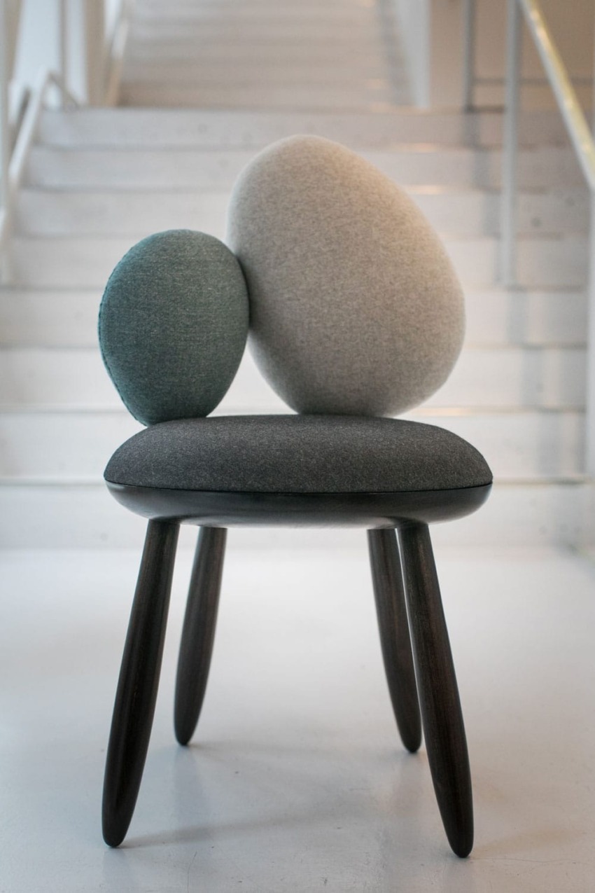 Modern chair with abstract, oval-shaped cushions in front of a staircase.