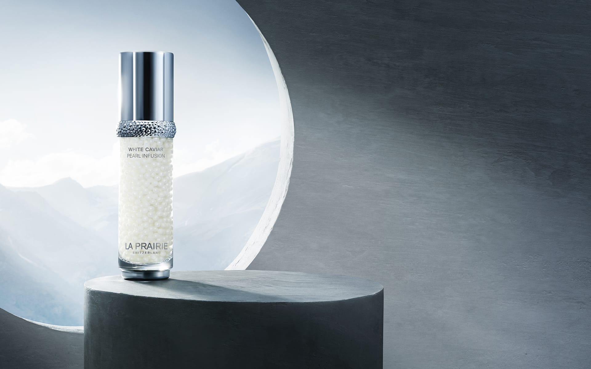 Luxury skincare bottle on gray pedestal with circular window, mountains visible in the background.