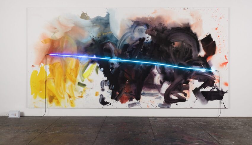 Abstract art with vibrant splashes of color and a blue neon light across the canvas, displayed on a gallery wall.