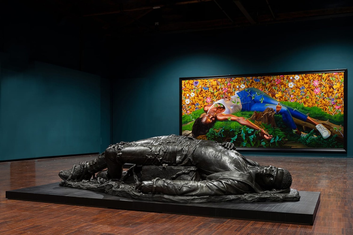 Bronze sculpture of a reclining figure in front of a colorful mural depicting a man lying in a field of flowers.