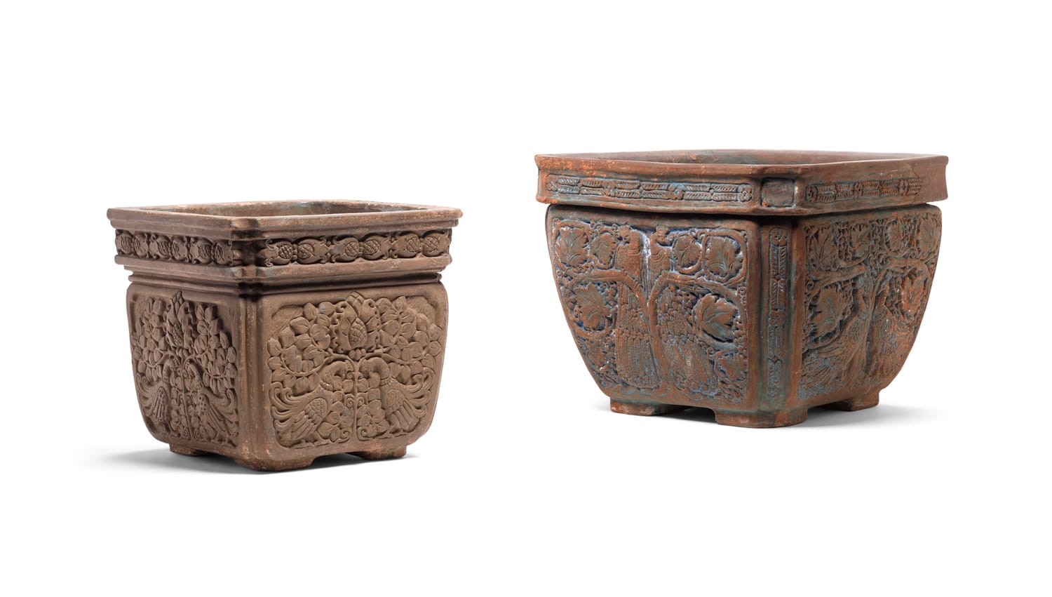 Two intricately carved square stone planters side by side, showcasing detailed patterns and textures.