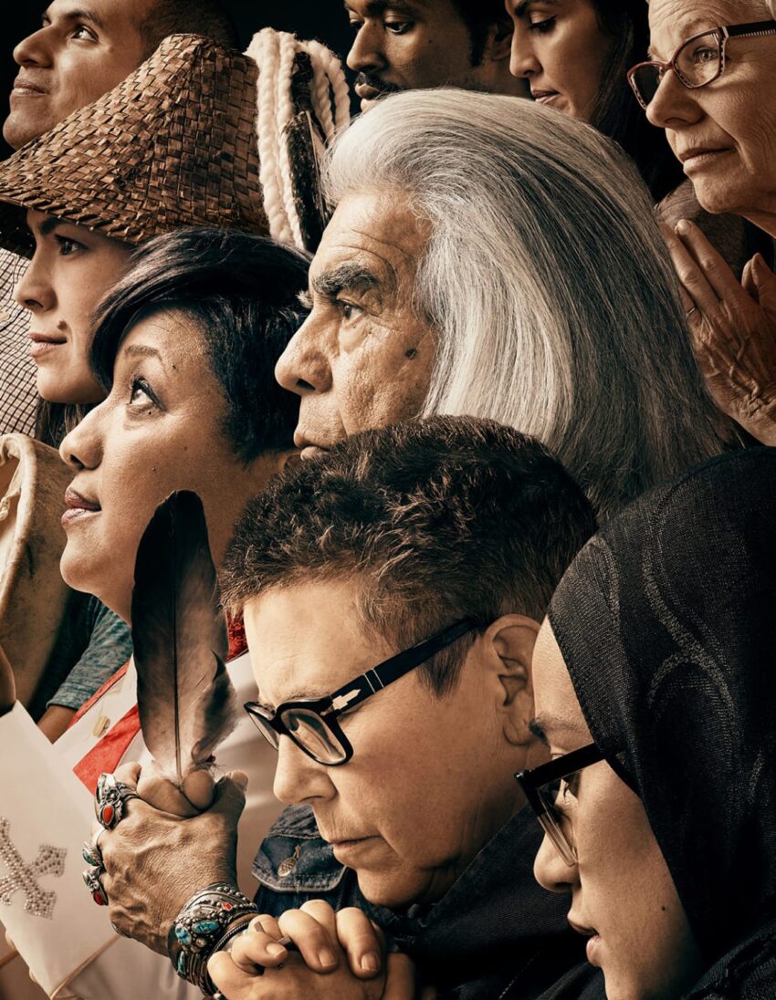 A diverse group of people standing together, each with unique attire, facing forward, conveying unity and diversity.