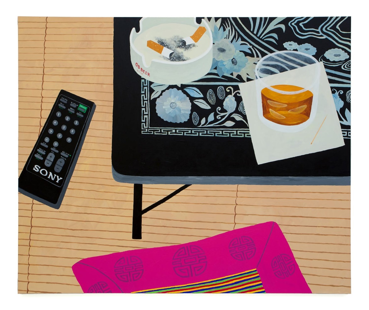 Table with a remote, ashtray, drink on a napkin, and decorative mat, atop a patterned floor with a bright pink cushion.