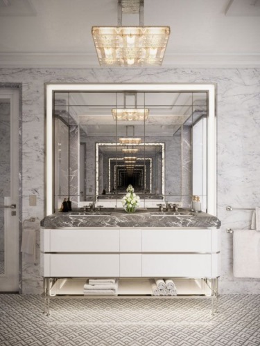 Luxurious bathroom with marble countertop, large mirror, elegant lighting, and towels neatly arranged on a shelf below.