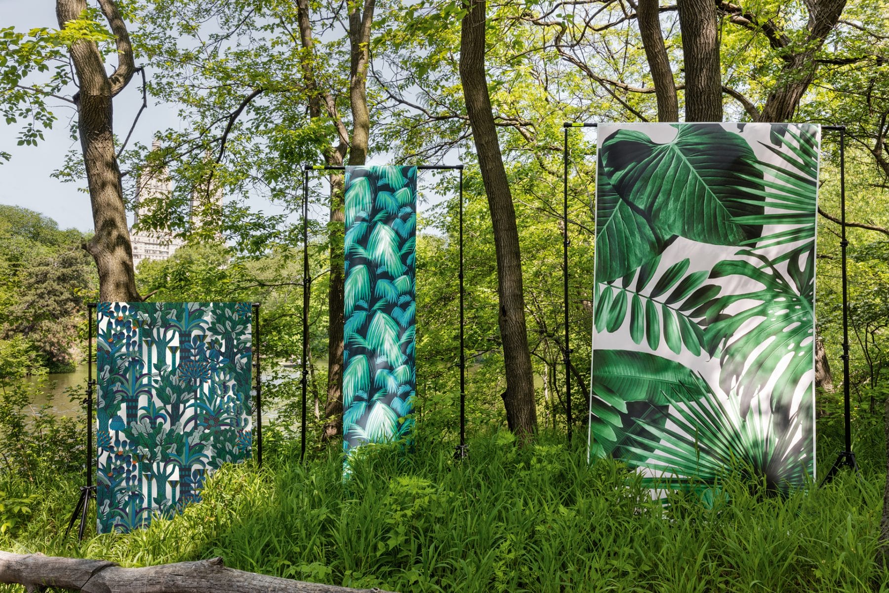 Three large panels with green leafy patterns stand amidst lush greenery and trees in a park setting.