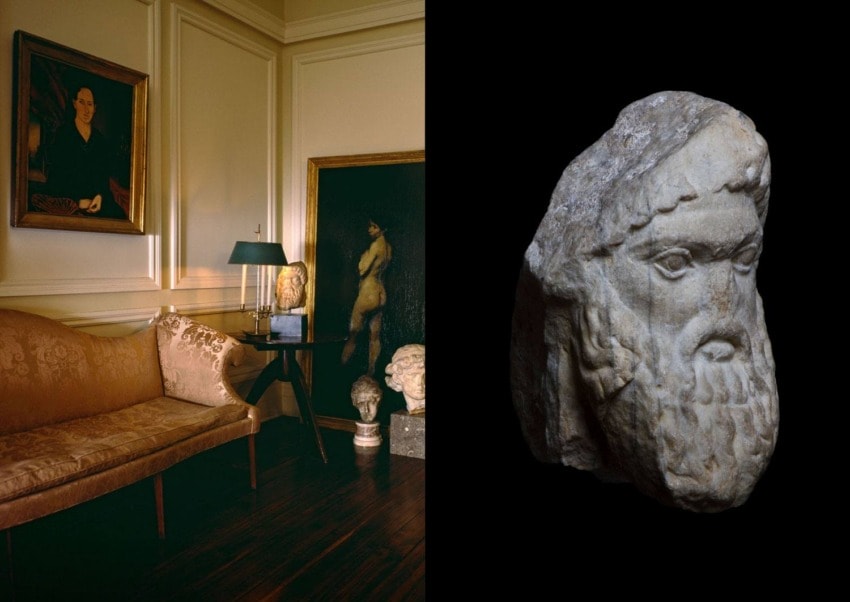 Elegant room with art, including a painting, sculptures, and a marble head bust on a dark background.