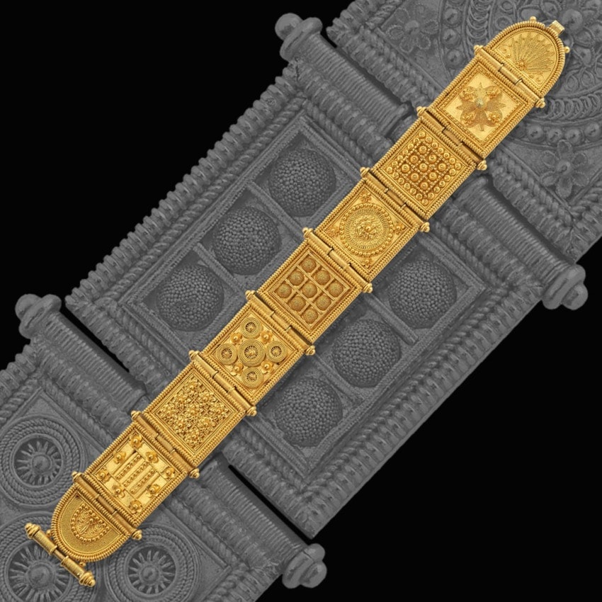Intricately designed gold bracelet with geometric and floral motifs on a textured background