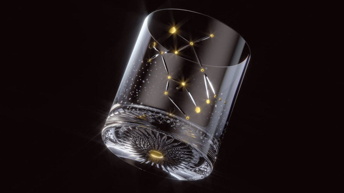Crystal tumbler with engraved constellation design and delicate golden accents against a dark background.