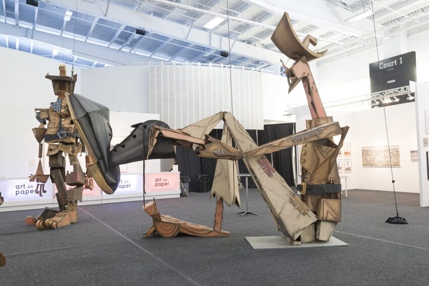 Large abstract cardboard sculpture in a modern art gallery with high ceilings and natural light.