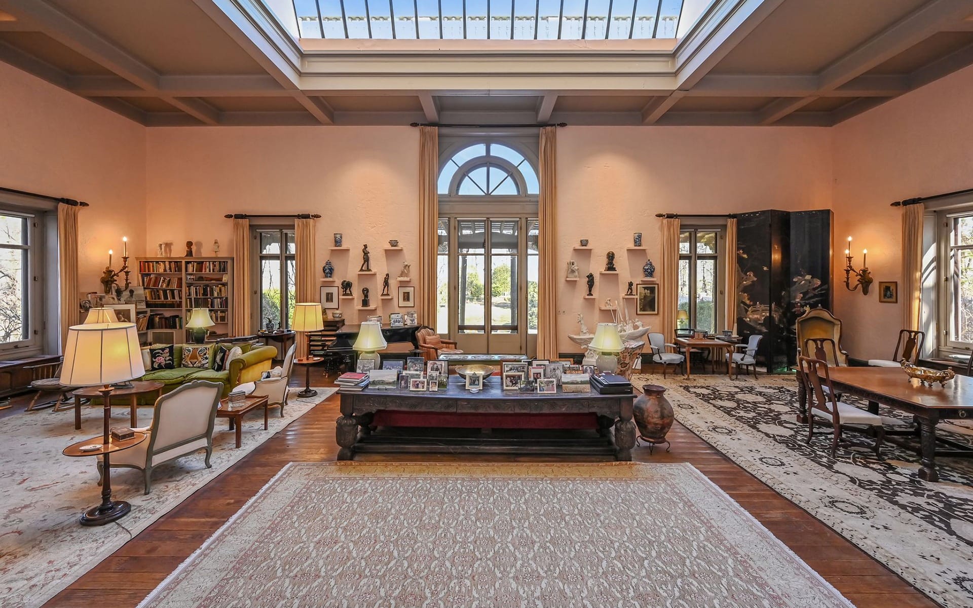 Spacious living room with skylight, elegant furniture, and a large rug, featuring large windows and decorative items.