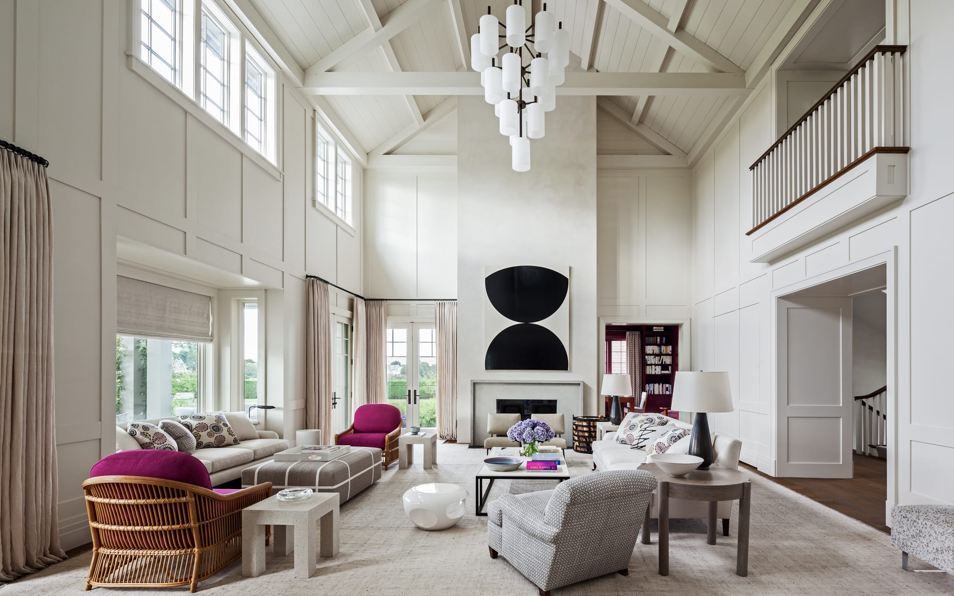 Spacious modern living room with high ceilings, eclectic furniture, large windows, and contemporary chandelier.
