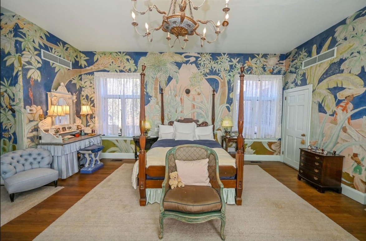 Eclectic bedroom with tropical-themed wall murals, a four-poster bed, and vintage furniture on a wooden floor.
