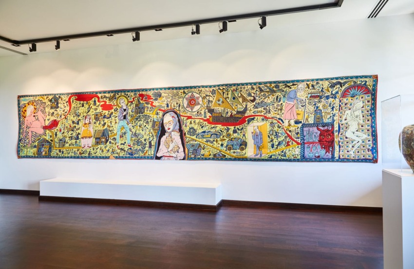 Colorful, intricate wall mural featuring various abstract and human figures in a modern art gallery setting.
