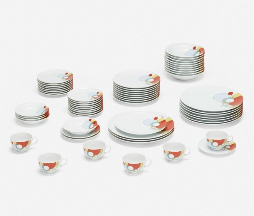 Colorful patterned dinnerware set with plates, bowls, and cups arranged in a geometric design.