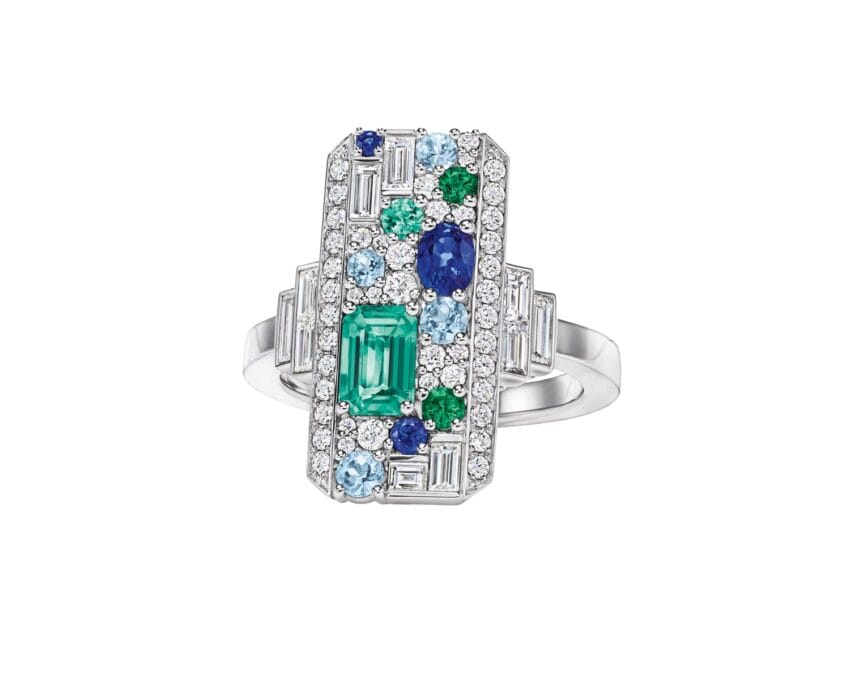 Rectangular gemstone ring with a central green emerald surrounded by blue, green, and white stones set in silver.