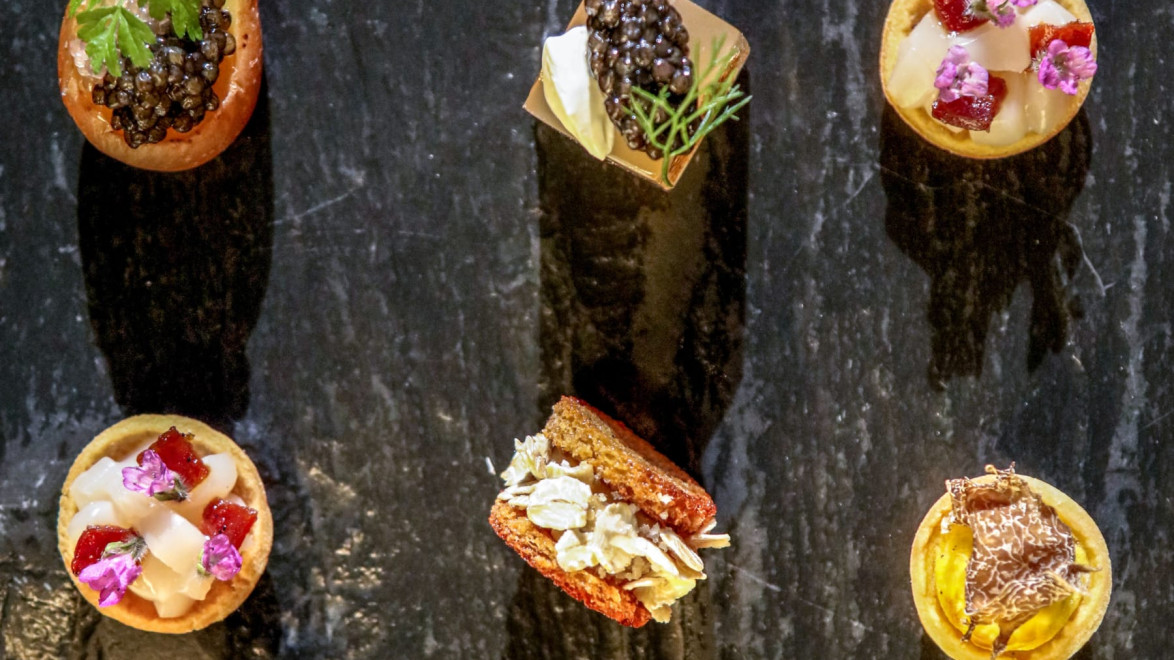 Assorted gourmet appetizers with various toppings on a dark slate background.