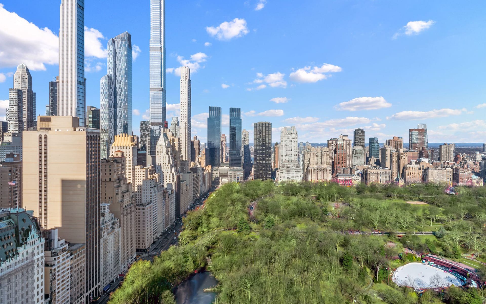 Aerial view of Central Park with surrounding skyscrapers and a blue sky background