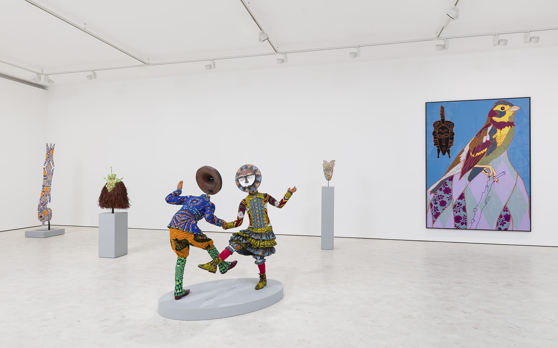 Art gallery with sculptures of two figures dancing, colorful artwork on walls, and various sculptures on pedestals.