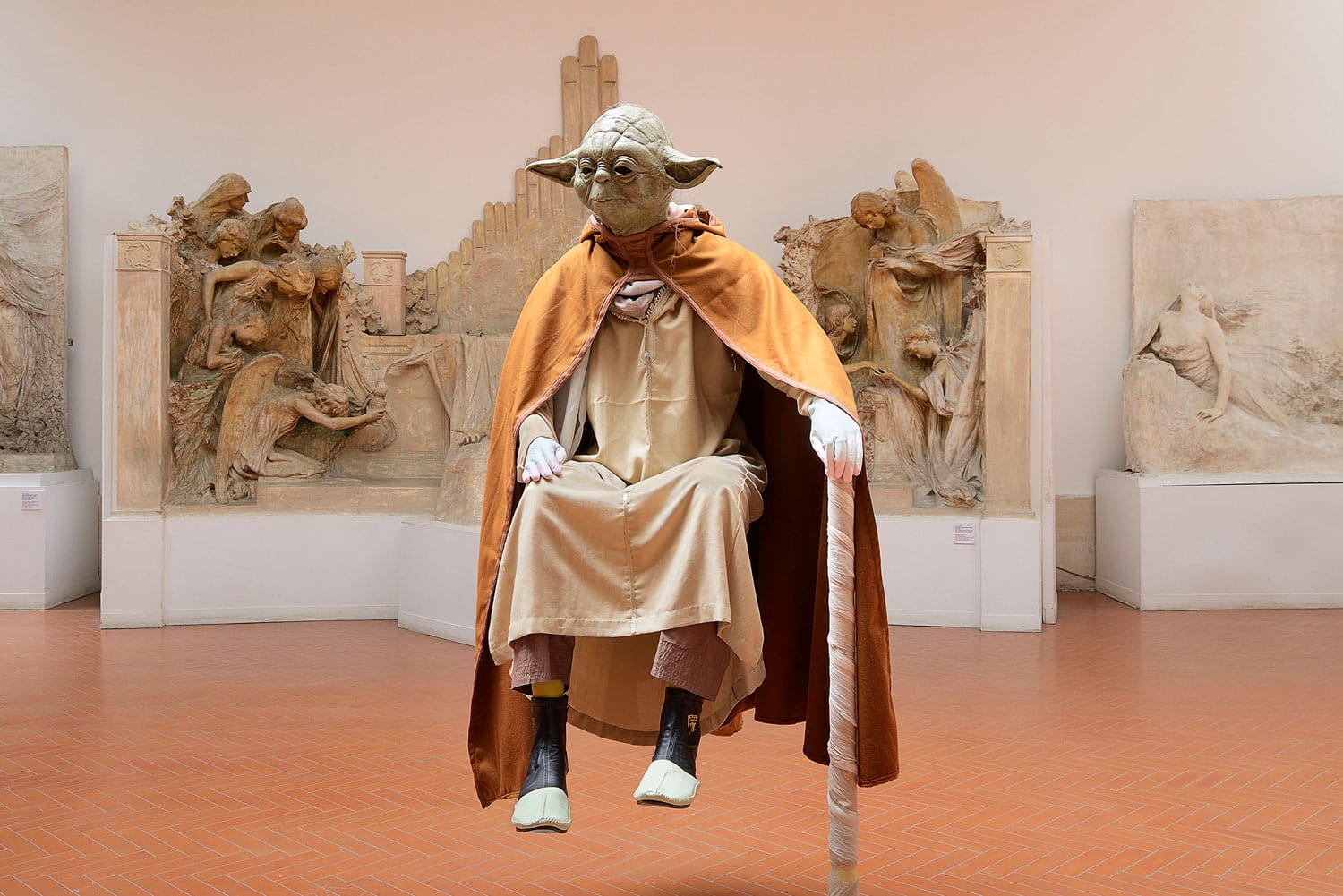 Levitation museum exhibit featuring a figure resembling a character in robes with a cane, surrounded by sculptures.
