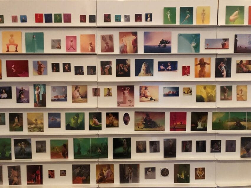 Gallery wall displaying various colorful photographs and art pieces arranged in multiple rows.