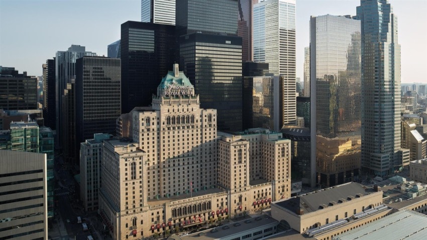 Historic hotel surrounded by modern skyscrapers in an urban cityscape during daylight.