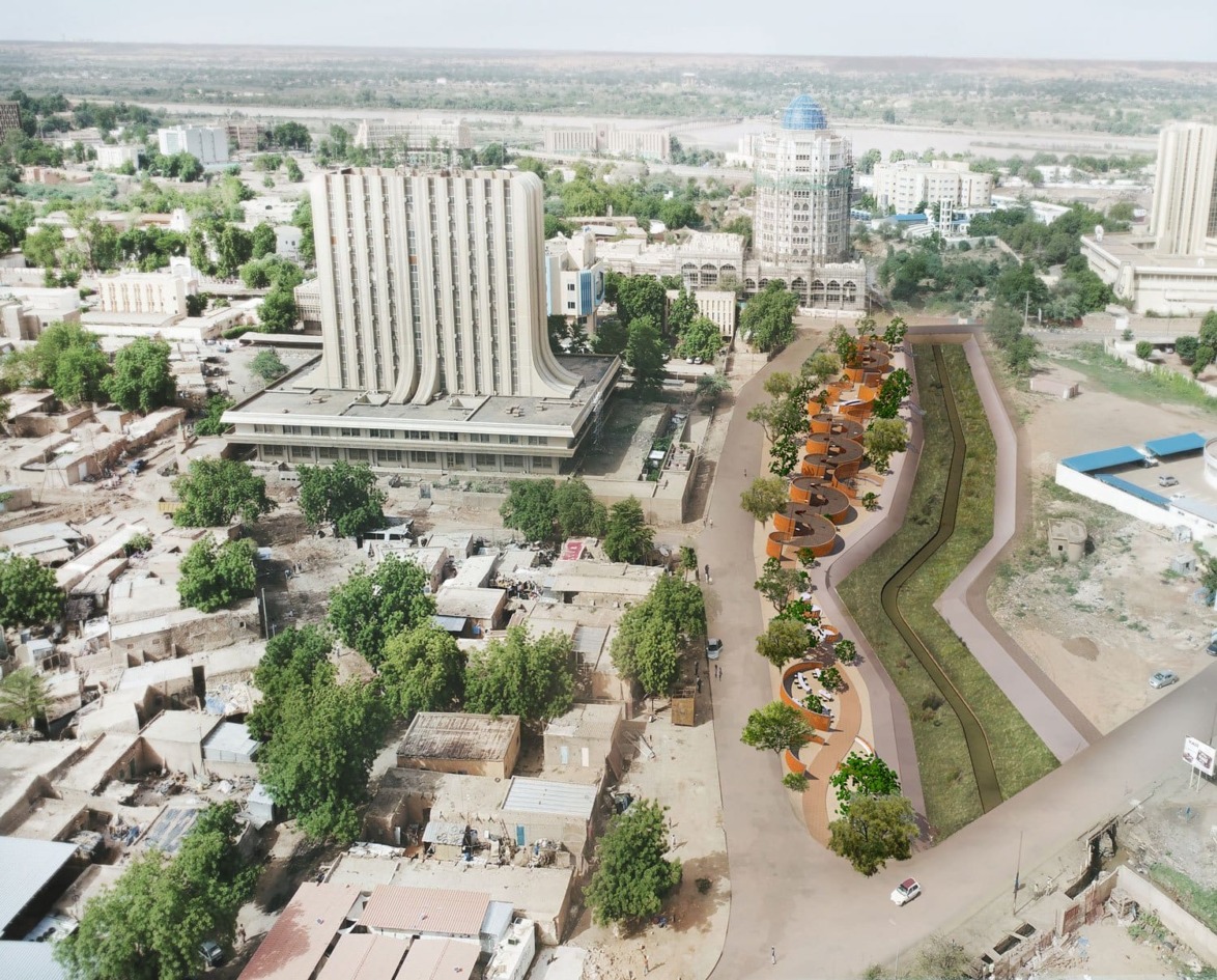 Aerial view of a cityscape with modern buildings, greenery, and a winding pathway.