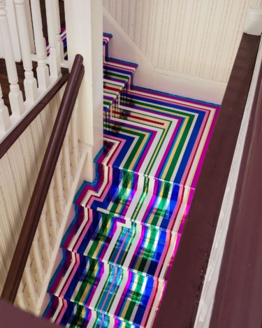 Colorful striped staircase with geometric design and white railing in a vintage house interior.