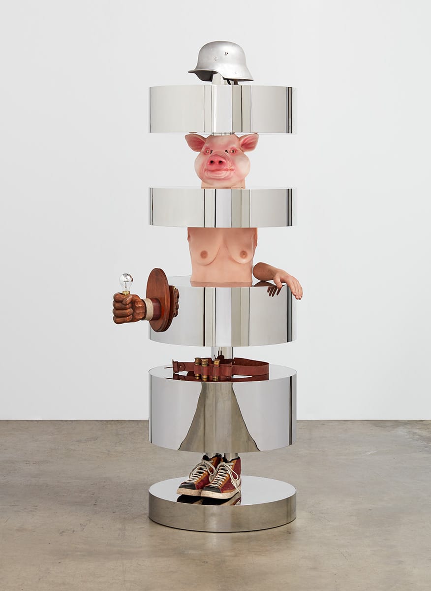 Surreal sculpture with segmented layers including a pig head, human torso, shoes, a football helmet, and industrial elements.