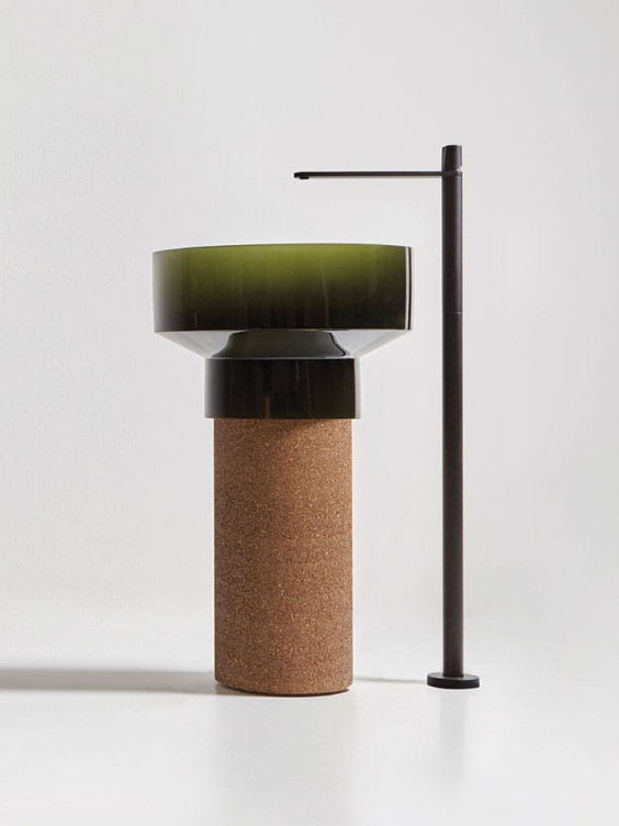 Modern pedestal sink with green basin, cork base, and sleek black faucet against a minimalist white background.