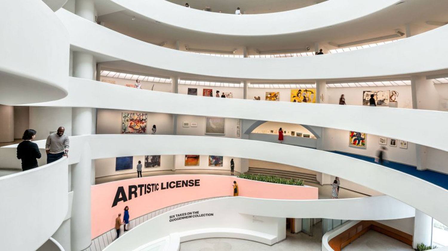 Interior view of modern museum with spiral ramps, visitors viewing art exhibits, and "Artistic License" displayed on the wall