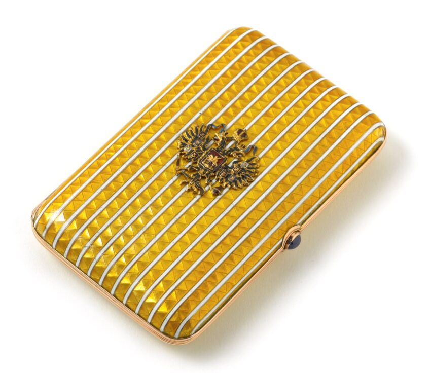 Yellow striped cigarette case with intricate crest design on a white background.