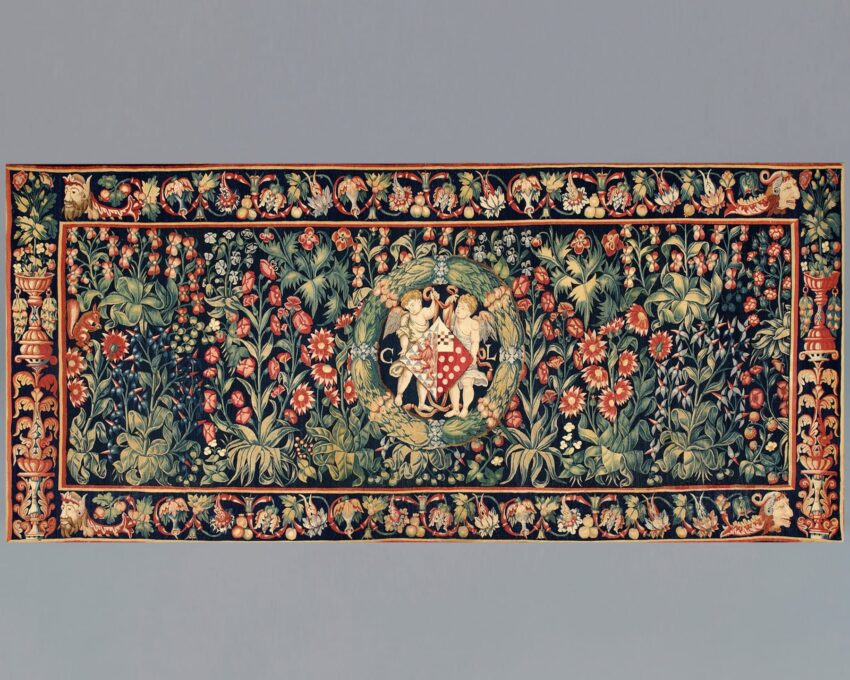 Medieval tapestry depicting intricate floral patterns and a central scene with two figures holding a shield.