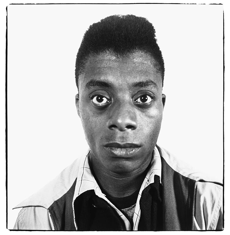 Black and white portrait of a person with a neutral expression, wearing a collared shirt and looking directly at the camera.