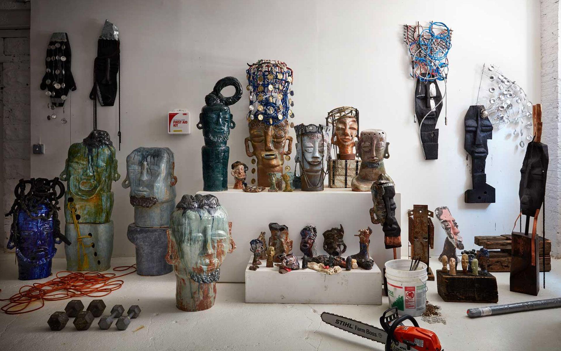 Art installation featuring various colorful sculptures on display in a studio with tools and materials scattered around.