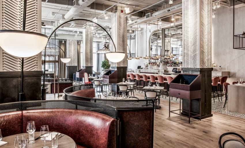 Upscale restaurant interior with modern decor, red leather seating, wooden floors, and a chic bar area.