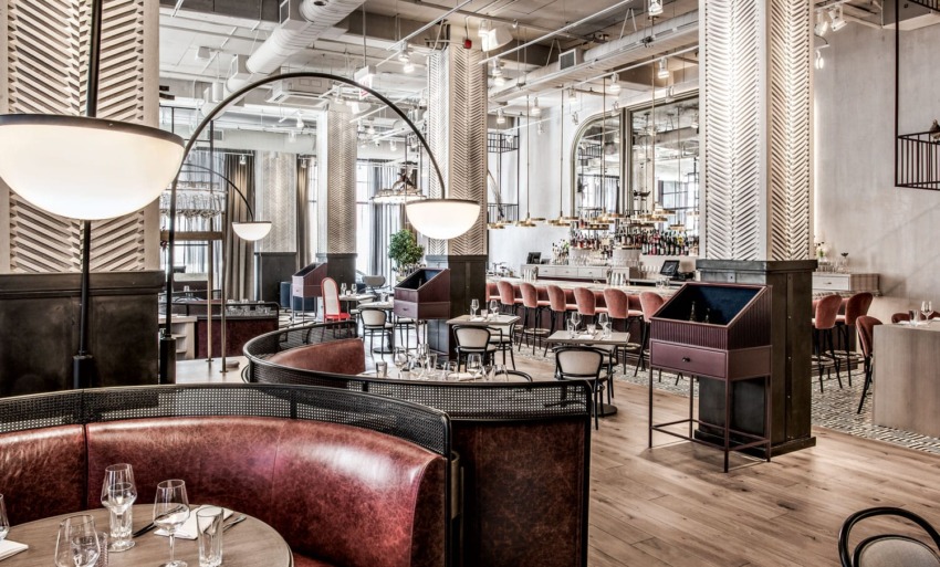 Upscale restaurant interior with modern decor, red leather seating, wooden floors, and a chic bar area.